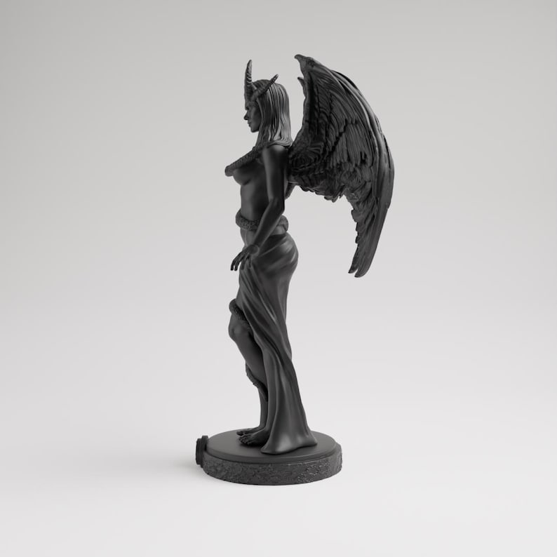 Op de afbeelding: Een zwarte sculptuur van een gevleugelde figuur met hoorns, een slang en vloeiende gewaden. Het beeld staat op een cirkelvormige basis, met gedetailleerde vleugels en een serene uitdrukking. De figuur is een donker, gotisch kunstwerk.