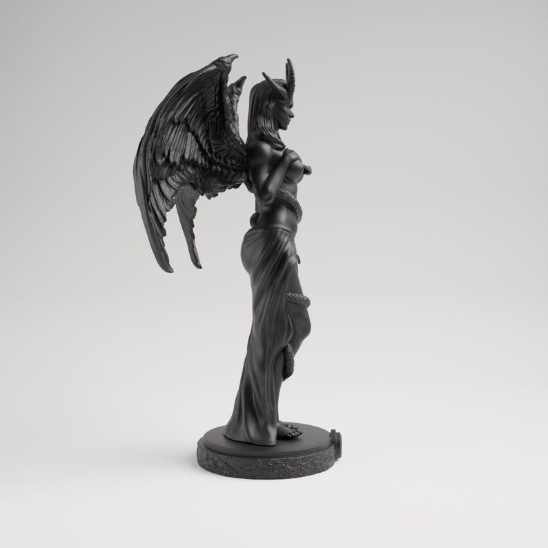 Op de afbeelding: Een zwarte sculptuur van een gevleugelde figuur met hoorns, gedrapeerd in vloeiende stof, en een slang om het lichaam gewikkeld. Het beeld staat op een ronde basis en heeft gedetailleerde, veerachtige vleugels.