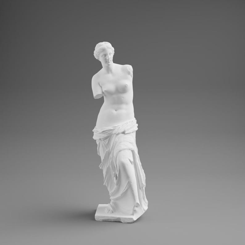 May include: A white plaster statue of Venus de Milo, a classical sculpture. The figure is depicted from the waist up, with the arms missing. The statue is draped in fabric and stands on a rectangular base against a gray background.