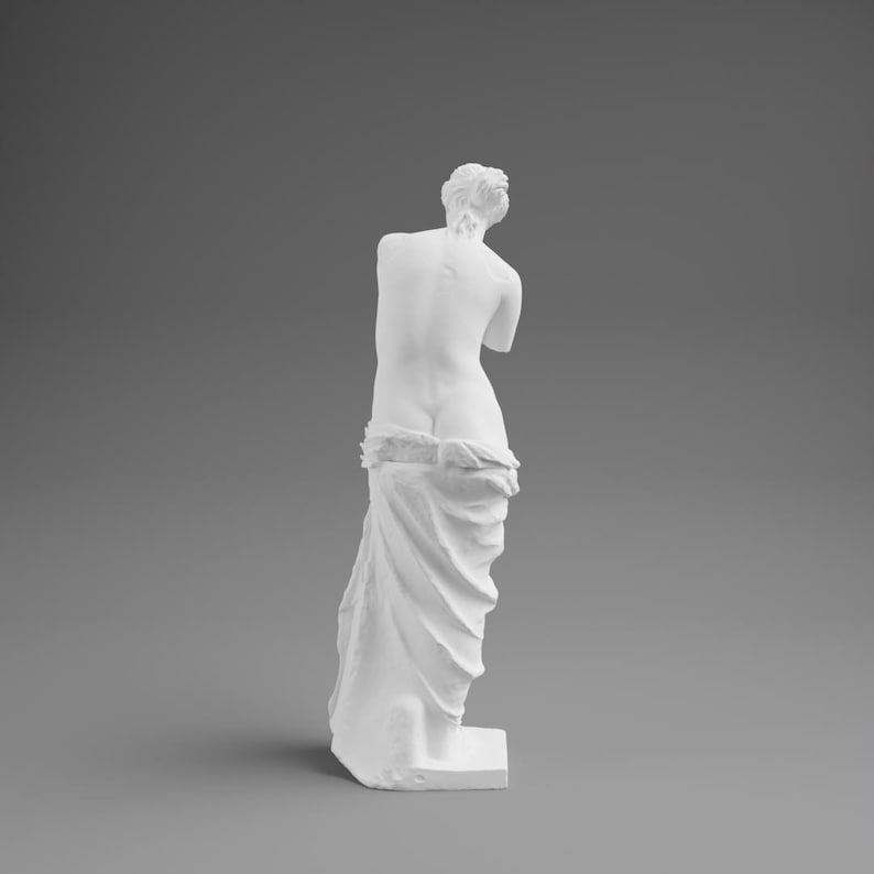 May include: A white sculpture of a classical female figure, viewed from the back. The figure is draped in fabric from the waist down, with the upper body exposed. The sculpture is set against a gray background.