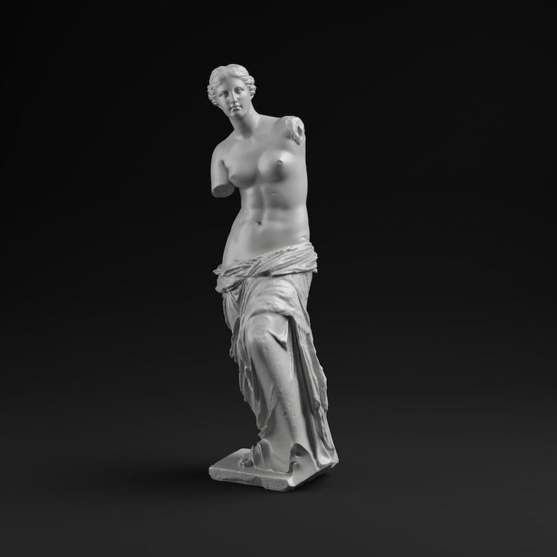May include: A white plaster statue of Venus de Milo, a classical sculpture. The statue is missing both arms and stands on a rectangular base. The figure is draped in fabric around the lower body, with a detailed depiction of the torso.