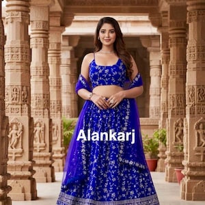 May include: A woman in a royal blue lehenga choli with detailed silver embroidery. The outfit comprises a crop top, a long skirt, and a sheer dupatta. The text "Alankarj" is visible on the skirt.