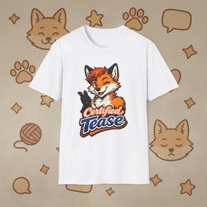 Puede incluir: Camiseta blanca con un zorro de dibujos animados guiñando un ojo y levantando el pulgar. El zorro es naranja, rojo y negro, con el texto "Certified Tease" en azul y blanco. La camiseta tiene cuello redondo.