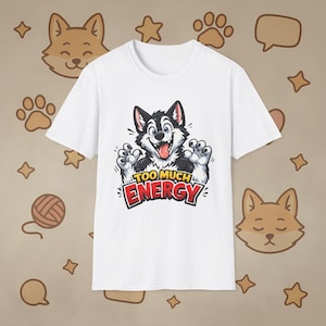 Op de afbeelding: Wit T-shirt met een cartoon husky ontwerp. De husky heeft een zwart-wit gezicht, poten en oren, en zijn tong steekt uit. De woorden "TOO MUCH ENERGY" staan in rood en geel.