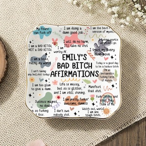 Könnte beinhalten: Eine weiße Keramikschale mit goldenem Rand, auf der "EMILY'S BAD BITCH AFFIRMATIONS" und verschiedene ermutigende Sätze in einem farbenfrohen, handschriftlichen Stil stehen. Die Schale ist mit floralen und Sternmotiven verziert.