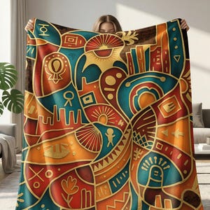 May include: A large rectangular throw blanket featuring a vibrant abstract pattern with bold teal, orange, and deep brown sections. The design includes various geometric shapes, stylized suns, and linear symbols outlined in gold, creating a complex visual composition across the entire surface of the fabric.