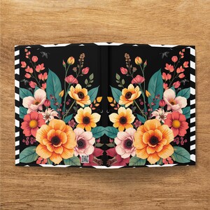 Floral pattern notebook cover with black and white striped edges on a wooden surface.