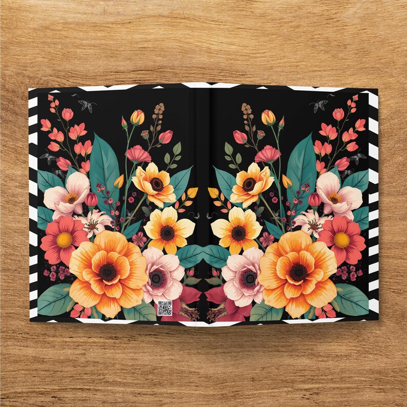 Floral pattern notebook cover with black and white striped edges on a wooden surface.