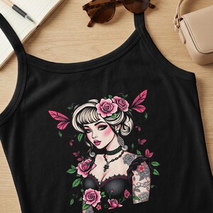 May include: Black tank top featuring a detailed illustration of a woman with a floral crown and tattoos. The artwork includes pink roses, green leaves, and a black choker necklace. The design has a vintage, gothic aesthetic.