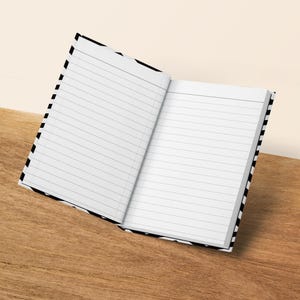 Open lined notebook with black and white striped cover on a wooden surface.