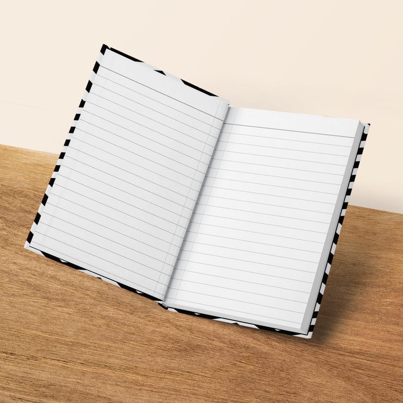 Open lined notebook with black and white striped cover on a wooden surface.