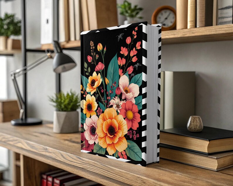 Black book with vibrant floral cover illustration, displayed on a wooden shelf.