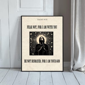 Può includere: Una stampa incorniciata con il testo "FEAR NOT, FOR I AM WITH YOU" e "BE NOT DISMAYED, FOR I AM YOUR GOD". L'immagine presenta un'illustrazione in bianco e nero di una figura con un'aureola, su uno sfondo a forma di stella. Il testo "ISAIAH 41:10" è in alto.