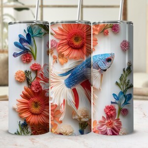 May include: Three stainless steel tumblers with a white background and colourful floral designs. The centre tumbler features a blue and white betta fish with a red and white tail.