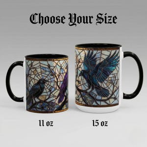 May include: Two ceramic mugs with black handles and rims. The mugs feature a stained-glass design with a raven perched on a branch. The text "Choose Your Size" is above the mugs. One mug is labeled "11 oz" and the other "15 oz".
