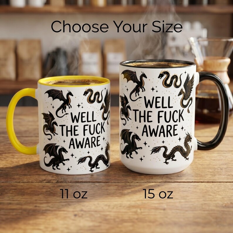May include: Two white ceramic mugs with black dragon illustrations and the text "WELL THE FUCK AWARE". One mug has a yellow handle and interior, the other has a black handle. Sizes are 11 oz and 15 oz.
