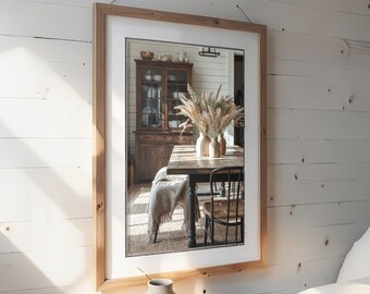 May include: A rectangular mirror with a light brown wooden frame hangs on a white wall. The mirror reflects a dining room scene with a wooden table, chairs, and a cabinet. A vase sits on a wooden side table.