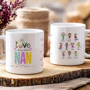May include: Two white ceramic mugs with handles. One mug has the text "I love being called Nan" with colorful letters and hearts. The other mug has a design of stick figures with names written below them.