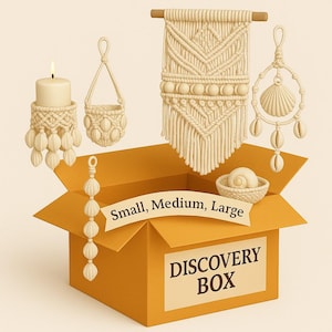 May include: An open orange box labeled "DISCOVERY BOX" contains several macrame home decor items. A candle holder, hanging basket, wall hanging, and seashell ornament are displayed. The box has a banner that reads "Small, Medium, Large".