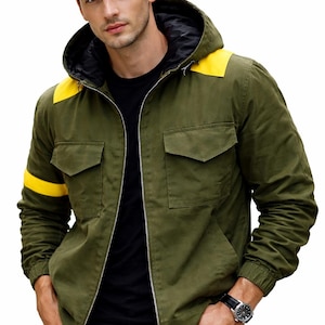May include: An olive green hooded jacket with yellow shoulder and sleeve stripes. The jacket has a black lining, two front pockets, and a full-length zip. The model is wearing a black top and black jeans.