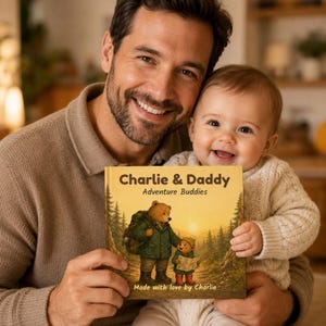 May include: A smiling man and baby hold a children's book titled "Charlie & Daddy Adventure Buddies." The book cover features a bear and cub in a forest scene. The text "Made with love by Charlie" is at the bottom.