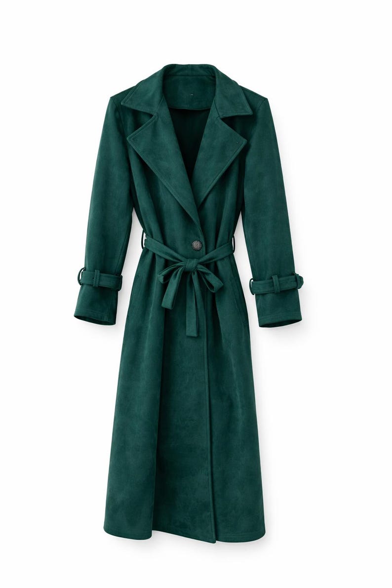 May include: A long, emerald green trench coat with a matching belt tied at the waist. The coat features a classic lapel collar, button closure, and long sleeves with cuff details. The coat is made of a soft, suede-like material.
