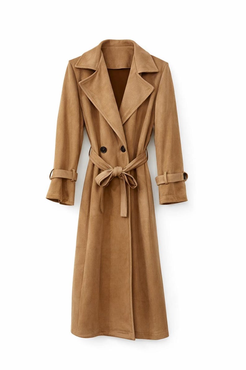 May include: A long, tan trench coat. It features a double-breasted closure, a matching belt, and sleeve straps. The coat has a classic lapel collar and is made of a soft, suede-like material. The coat is a neutral colour and is suitable for various occasions.