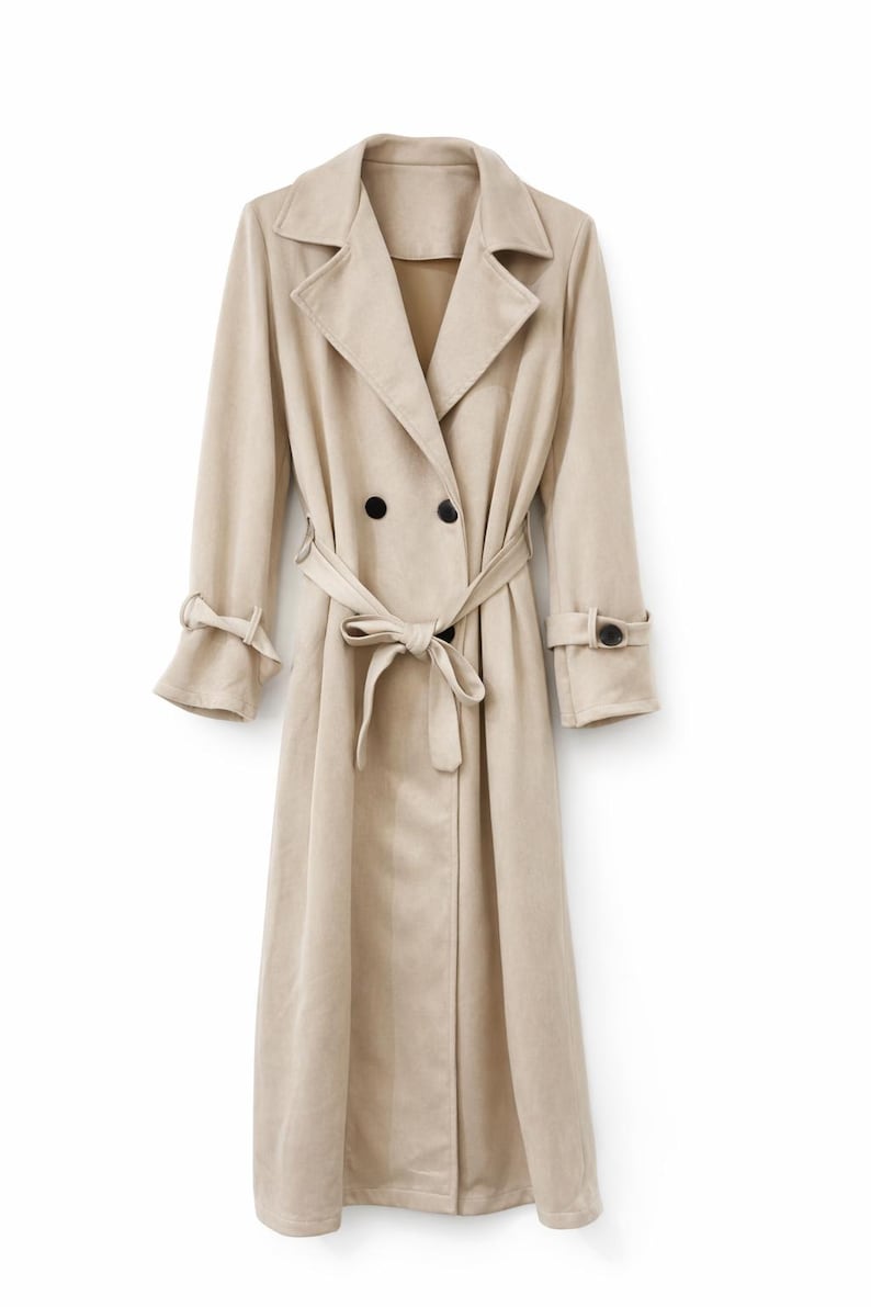 May include: A beige trench coat with a double-breasted design, featuring a notched collar, long sleeves, and a matching belt tied at the waist. The coat has black buttons and cuff details, offering a classic and elegant look.