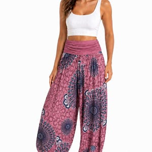 May include: A woman wearing a white crop top and pink harem trousers. The trousers feature a mandala-style pattern in shades of blue and pink. The trousers have a wide, gathered waistband.