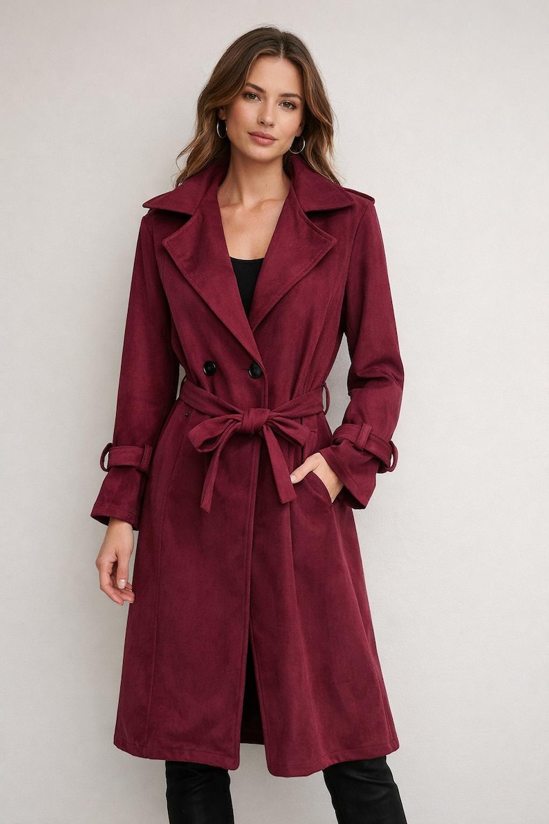 May include: A burgundy trench coat with a double-breasted front, a matching belt, and long sleeves. The coat features a notched collar, pockets, and buttoned cuffs. The coat is approximately 140 cm long.