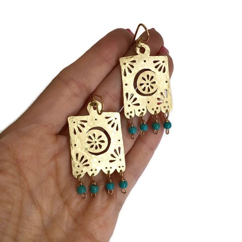 May include: Gold earrings with a cutout design and turquoise beads hanging from the bottom.