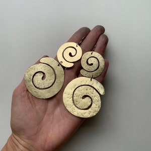 May include: A pair of gold-toned earrings with a spiral design. Each earring has two spirals, one larger than the other.