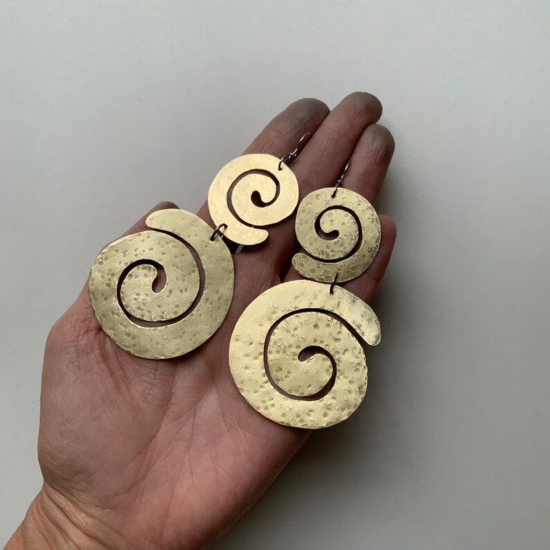 May include: A pair of gold-toned earrings with a spiral design. Each earring has two spirals, one larger than the other.