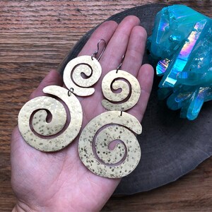 May include: A pair of gold-toned earrings with a hammered finish. Each earring features a double spiral design.