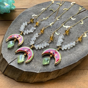 May include: Three gold necklaces with watermelon crescent moon pendants. Each necklace features white beads and gold accents. The watermelon pendants are red, green, and black with gold details.