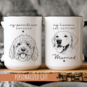 Peut inclure: Deux mugs en céramique blancs avec des anses et des bords noirs. L'un présente une illustration de chien doodle et le texte "my parents are engaged". L'autre mug a une illustration de Labrador et le texte "my humans are getting married."