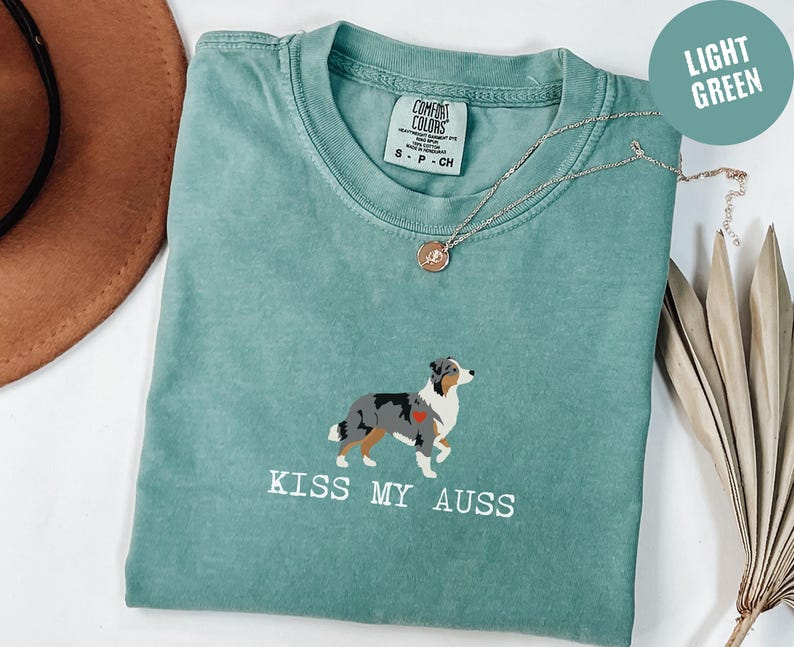 comfort colors t-shirt with small centered Blue Merle Australian Shepherd illustration above the phrase “Kiss My Auss”