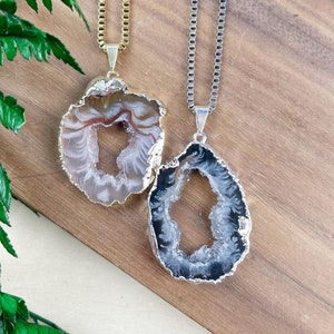 May include: Two agate slice necklaces with gold and silver chains. The agate slices are both white with a clear center and have a natural, organic shape.