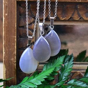 May include: Three silver chain necklaces with teardrop-shaped pendants made of light gray agate.