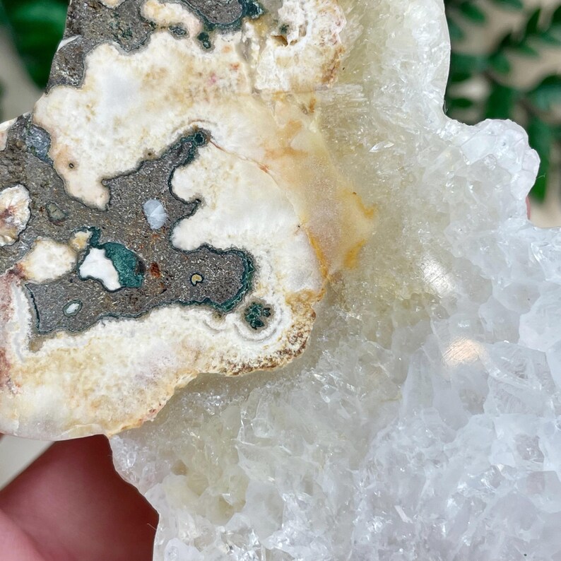 K&ouml;nnte beinhalten: Ein wei&szlig;er und gr&uuml;ner Achatkristall mit einem Cluster aus klaren Quarzkristallen. Der Achat hat ein wirbelndes Muster aus Wei&szlig;, Gr&uuml;n und Braun.