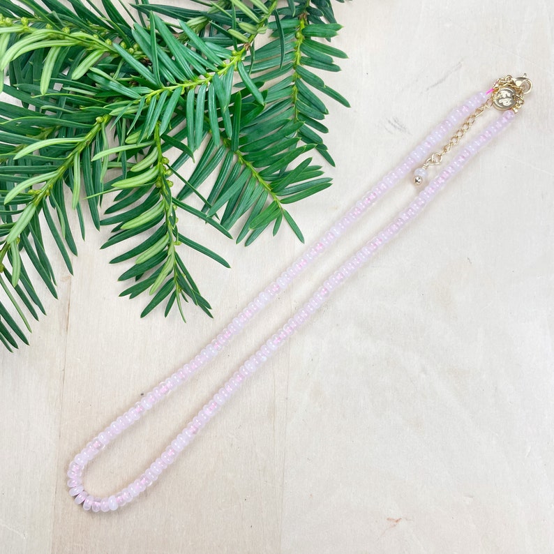 May include: A delicate pink beaded necklace with a gold clasp. The necklace is made of small, round beads and is approximately 18 inches long.