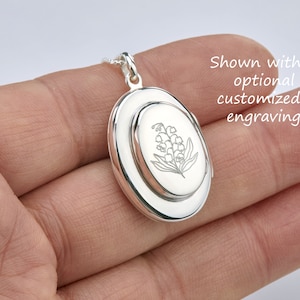 May include: Silver oval locket necklace with a delicate engraved lily of the valley design. Shown with optional customized engraving.