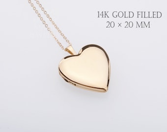 May include: A 14K gold filled heart-shaped locket pendant on a delicate gold chain. The locket measures 20 x 20 mm. The surface of the heart is smooth and polished, reflecting light, with a small hinge visible on the side of the metal casing.