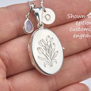 May include: Silver locket necklace with a tulip engraving. The locket has a small, clear teardrop charm and a round charm with the letter "D" engraved on it. Shown with optional customized engraving.