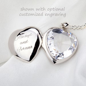 Puede incluir: Un medallón de plata en forma de corazón con un corazón de cristal transparente en la parte delantera. El medallón está abierto y el interior está grabado con las palabras "Always and Forever".