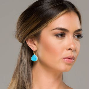 May include: A pair of gold dangle earrings with turquoise teardrop-shaped stones.