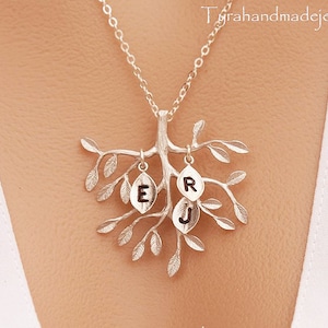 May include: Silver necklace with a tree pendant and three leaves with the letters E, R, and J on them.