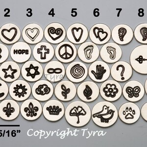 May include: A set of 40 silver metal charm discs with various symbols and designs, including hearts, stars, peace signs, and religious symbols. The discs are 5/16 inches in diameter. Copyright Tyra.