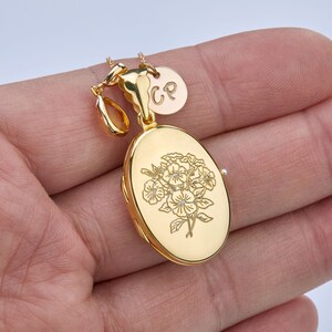 May include: Gold oval locket necklace with a floral design and a small charm with the initials "CP".