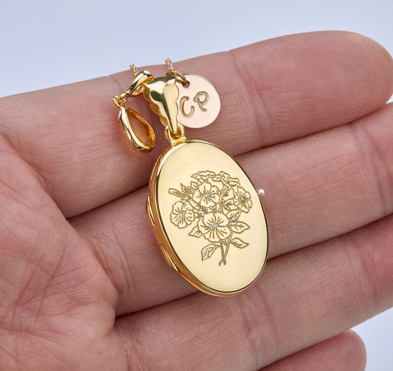 May include: Gold oval locket necklace with a floral design and a small charm with the initials "CP".